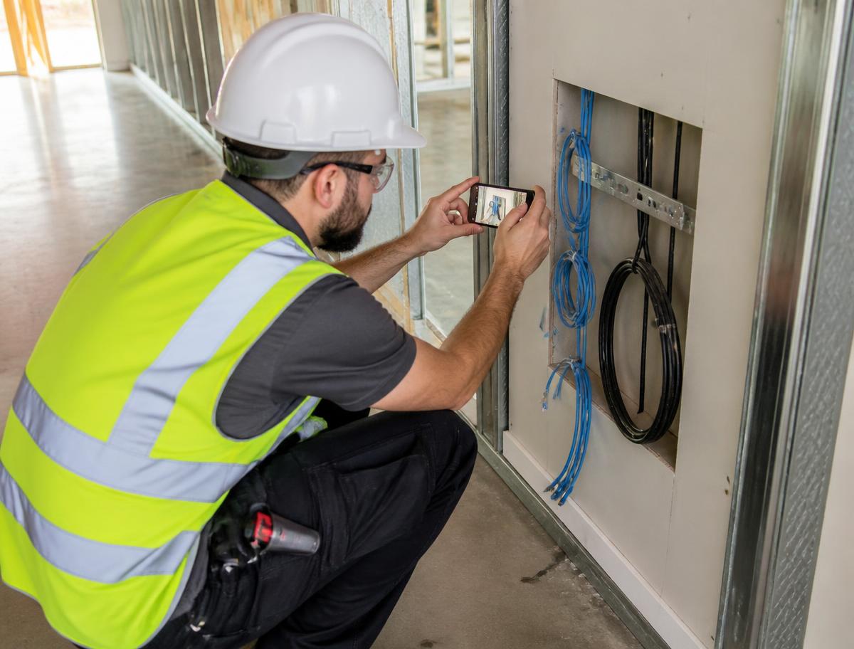 Technician photographing low-voltage cabling at a commercial jobsite